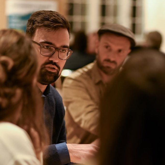 Politischer Abend des LJR Männliche Teilnehmer in einem Gespräch bei einer Diskussion, in einem gemütlichen Raum.