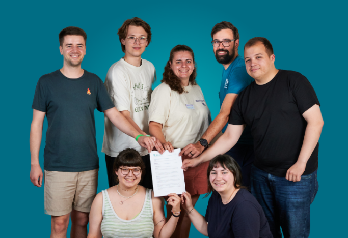 KjG - Bundessatzungsausschuss Gruppe von sieben Personen posiert gemeinsam und hält ein Dokument in der Mitte.